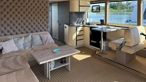 Un espace de vie compact comprenant un canapé, une petite table, un coin cuisine et une vue sur l’eau.