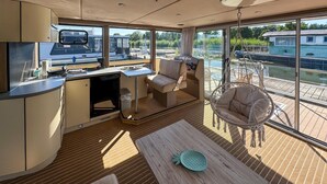 Une vaste terrasse dotée d’un espace repas, d’un fauteuil suspendu et offrant une vue sur un plan d’eau.