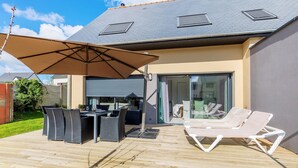 A covered patio with outdoor furniture, a grill, and a sliding glass door leading to a room.