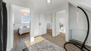 A modern, well-lit room with a bed, a large window, and a hanging light fixture.