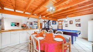 A cozy dining area with a pool table, wooden ceiling beams, and a white tiled floor. - Beautiful home in Rioux (Rioux)