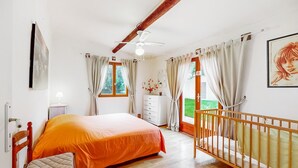 A bedroom with a bed, a crib, a dresser, a ceiling fan, and a window with curtains. - Beautiful home in Rioux (Rioux)