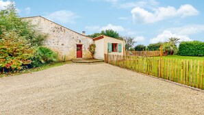A gravel driveway leading to a stone building with a red door and a small attached structure with a red window. - Beautiful home in Rioux (Rioux)