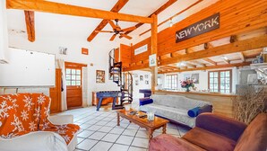 A spacious living room with a high ceiling, wooden beams, a sofa, a coffee table, and a fireplace. - Beautiful home in Rioux (Rioux)