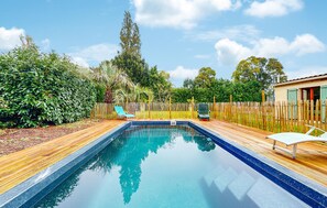A rectangular swimming pool with a wooden deck surrounding it, a wooden fence, and a small building with a window. - Stunning home in Rioux with private swimming pool, can be inside or outside (Rioux)