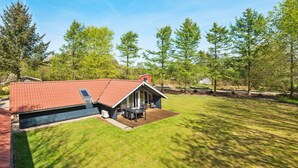 Een modern huis met een rood dak, een terras en een gazon.