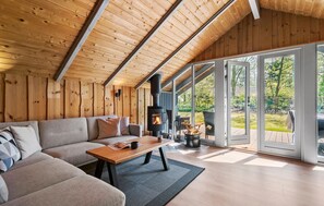 A cozy living room with a wooden ceiling, a sofa, a coffee table, and a fireplace.