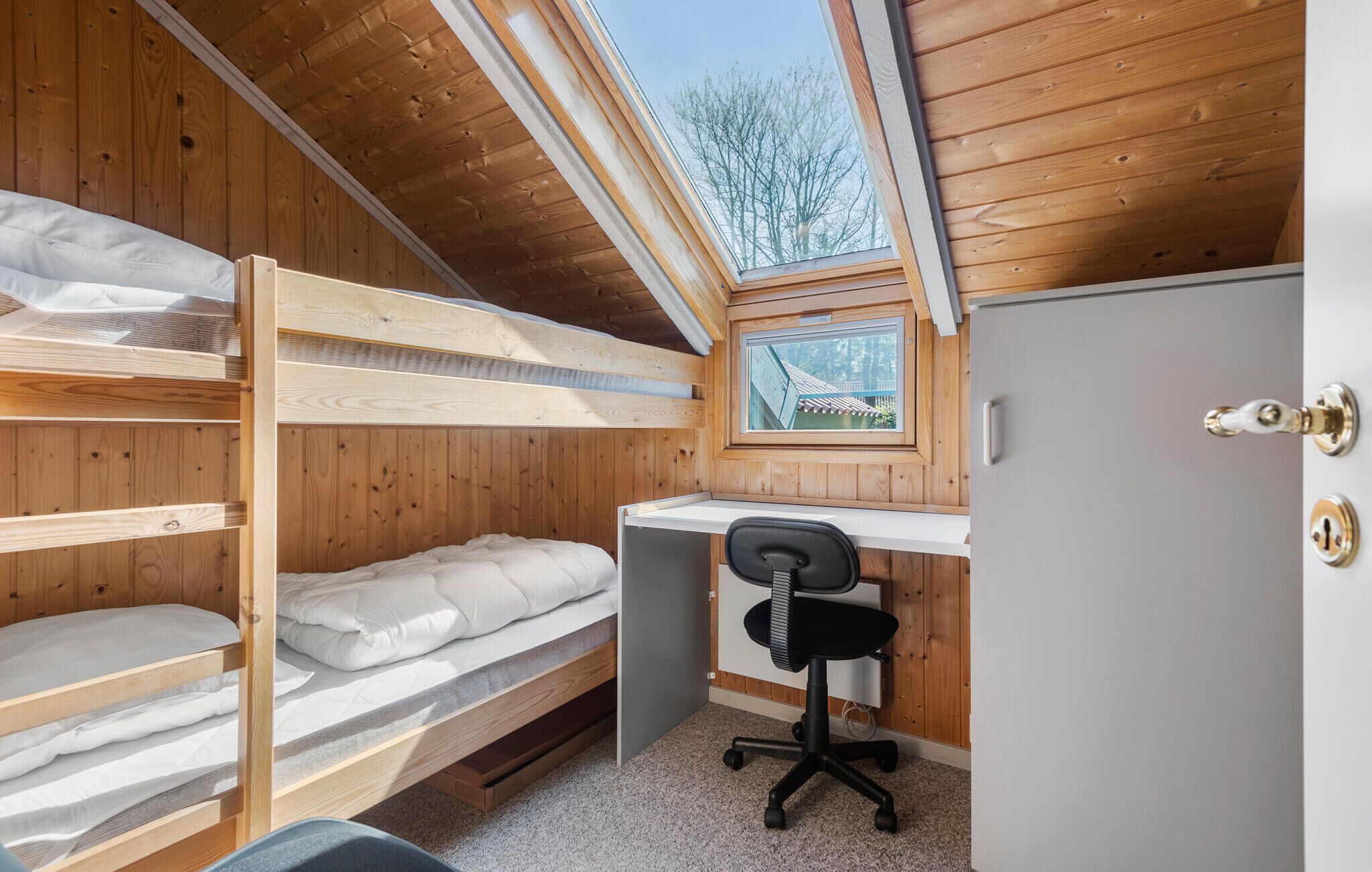 Una habitación pequeña con literas, un escritorio y una silla.