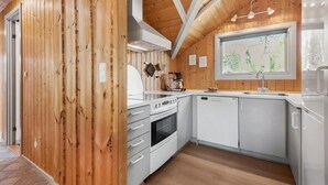 Een moderne keuken met houten wanden, witte kasten en een groot raam met uitzicht op groen.