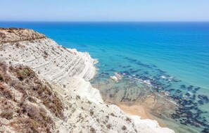 Un paisaje costero con un acantilado rocoso y mar azul cristalino.