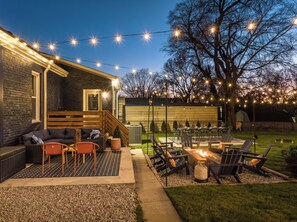 A backyard with a fire pit, outdoor seating, and string lights. - The Nashville Getaway - Huge Backyard, Fire Pit, Movie & Game Room  (Nashville)