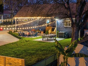 A backyard with a barbecue area, outdoor seating, and string lights.