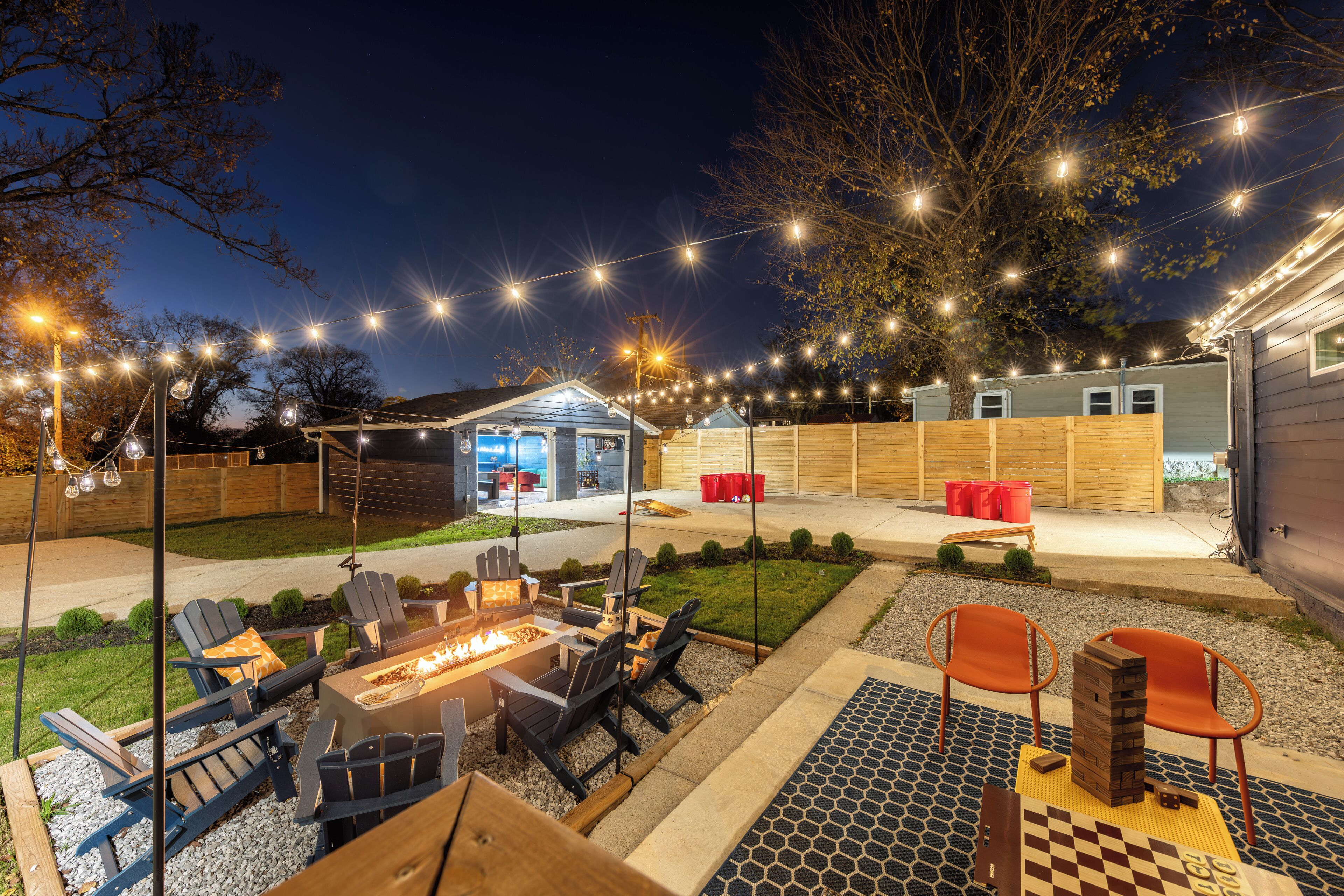Un patio al aire libre con un brasero, asientos e iluminación con guirnaldas.