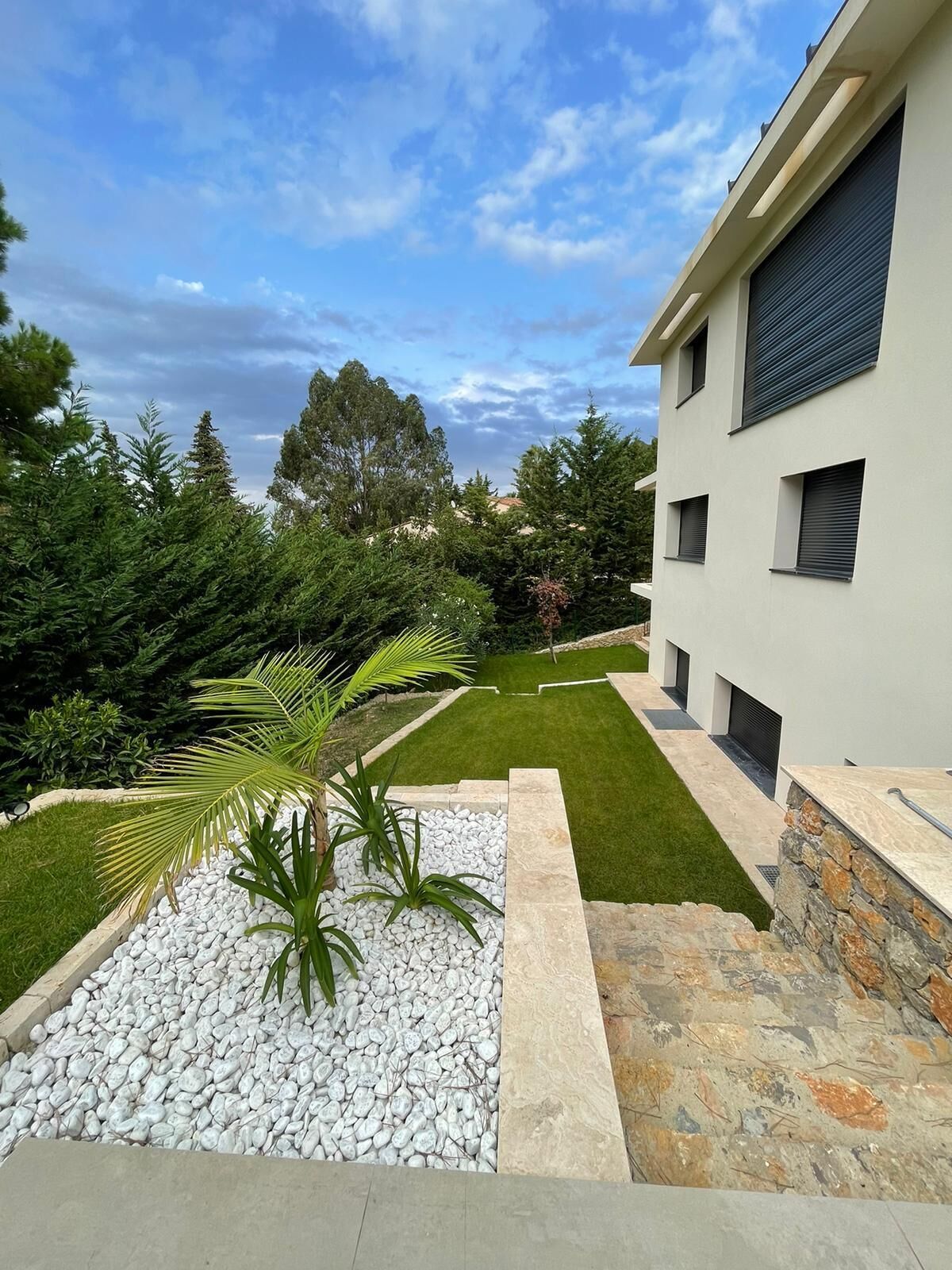 A modern building with a well-maintained lawn and a stone pathway leading to the entrance.