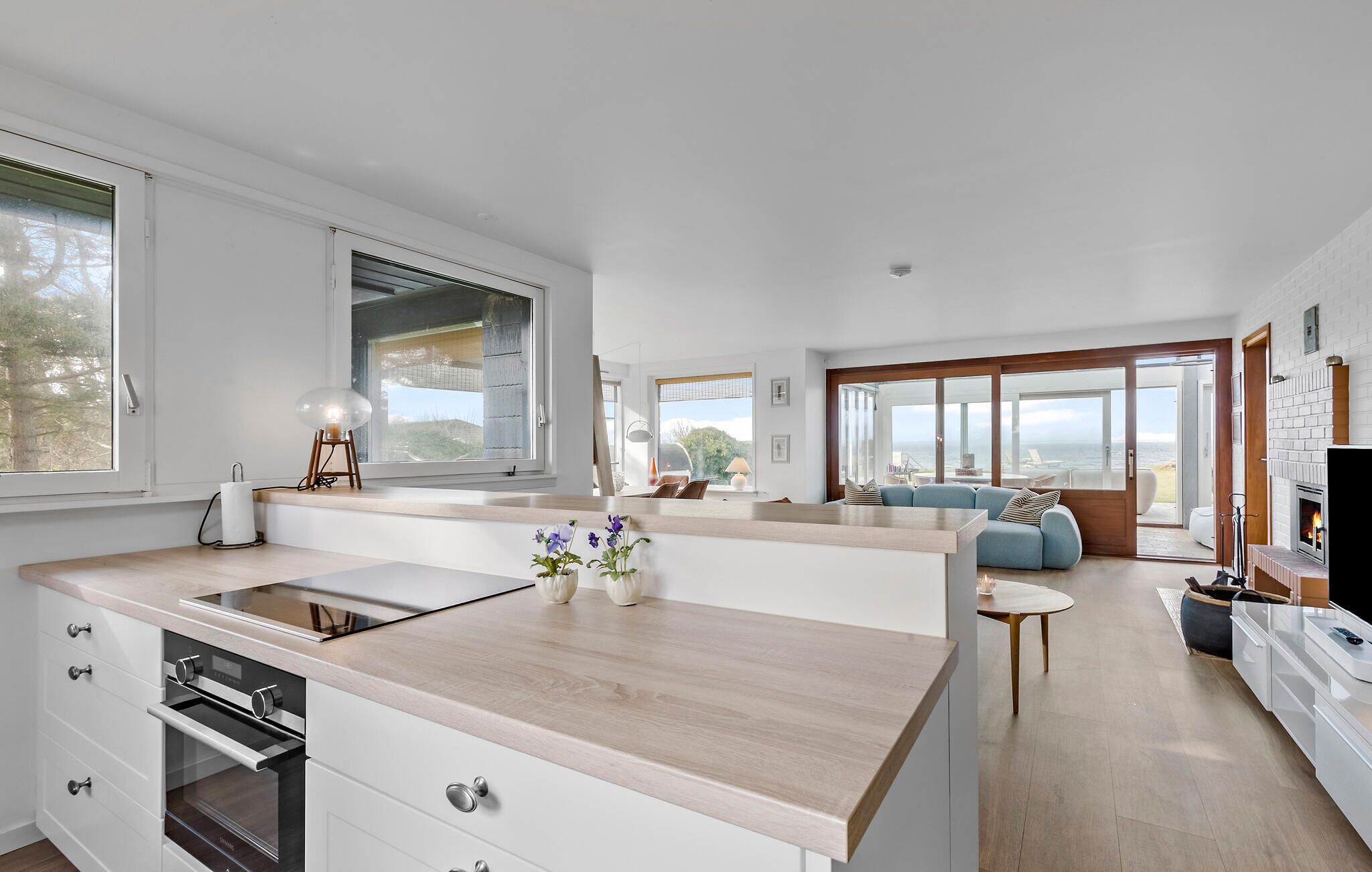 A modern kitchen with a central island, large windows, and a view of the outdoors.