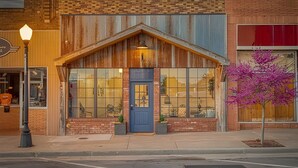 A building with a blue door, large windows, and a small porch area. - Bluebird Place Jessie Room: Historic Rt 66 (Elk City)