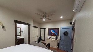 A bedroom with a bed, a desk, a chair, a television, and a ceiling fan. - Bluebird Place Jessie Room: Historic Rt 66 (Elk City)