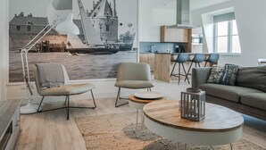 Una sala de estar moderna con un mural de un velero, una mesa de centro redonda y un sofá.