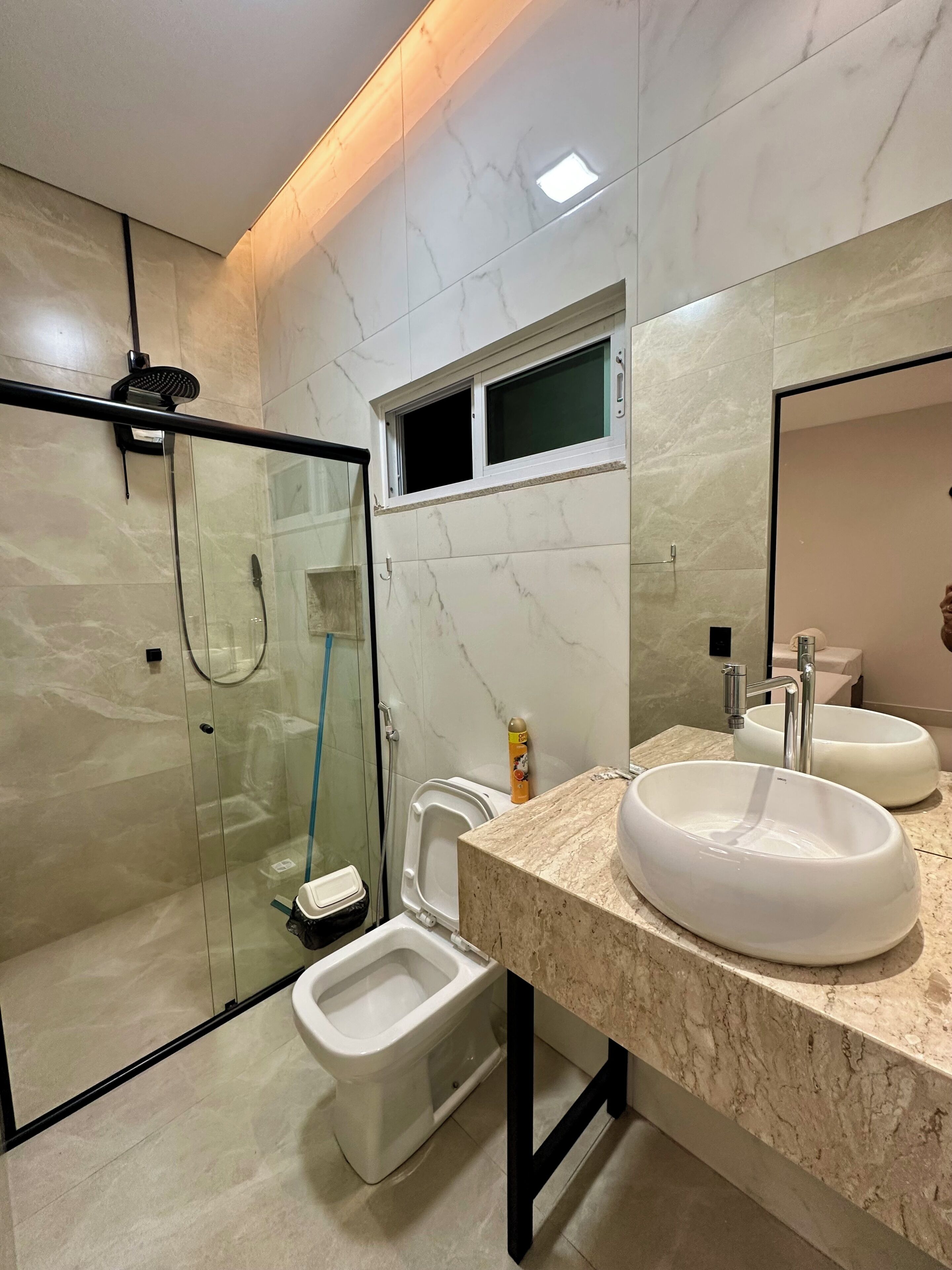 Een moderne badkamer met een douchecabine van glas, een toilet en een wastafel met twee wasbakken.