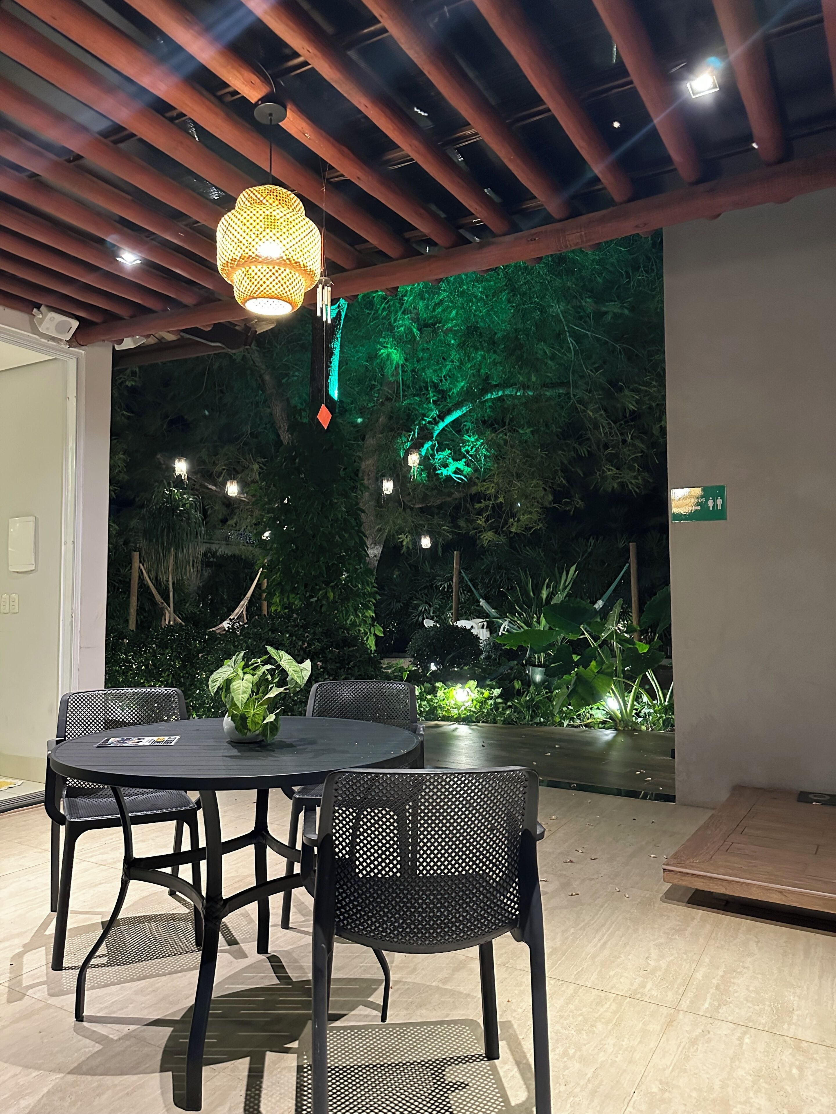 Un comedor interior con una mesa redonda, sillas de malla negra y una lámpara colgante.