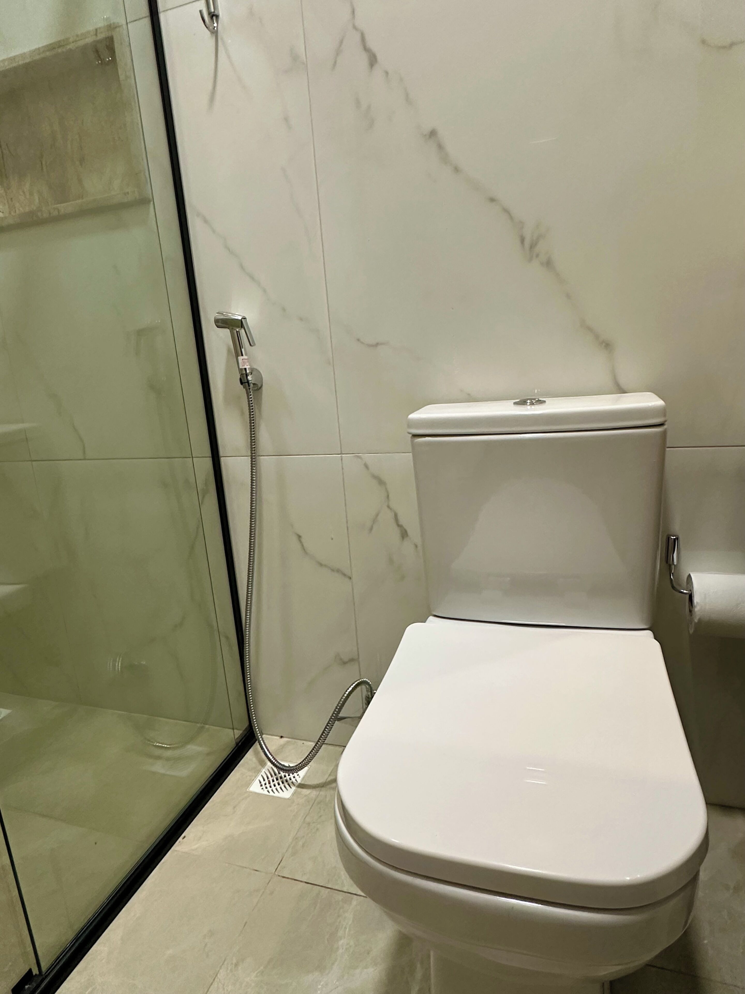 Un baño con inodoro, ducha y cabina de ducha con paredes de vidrio.