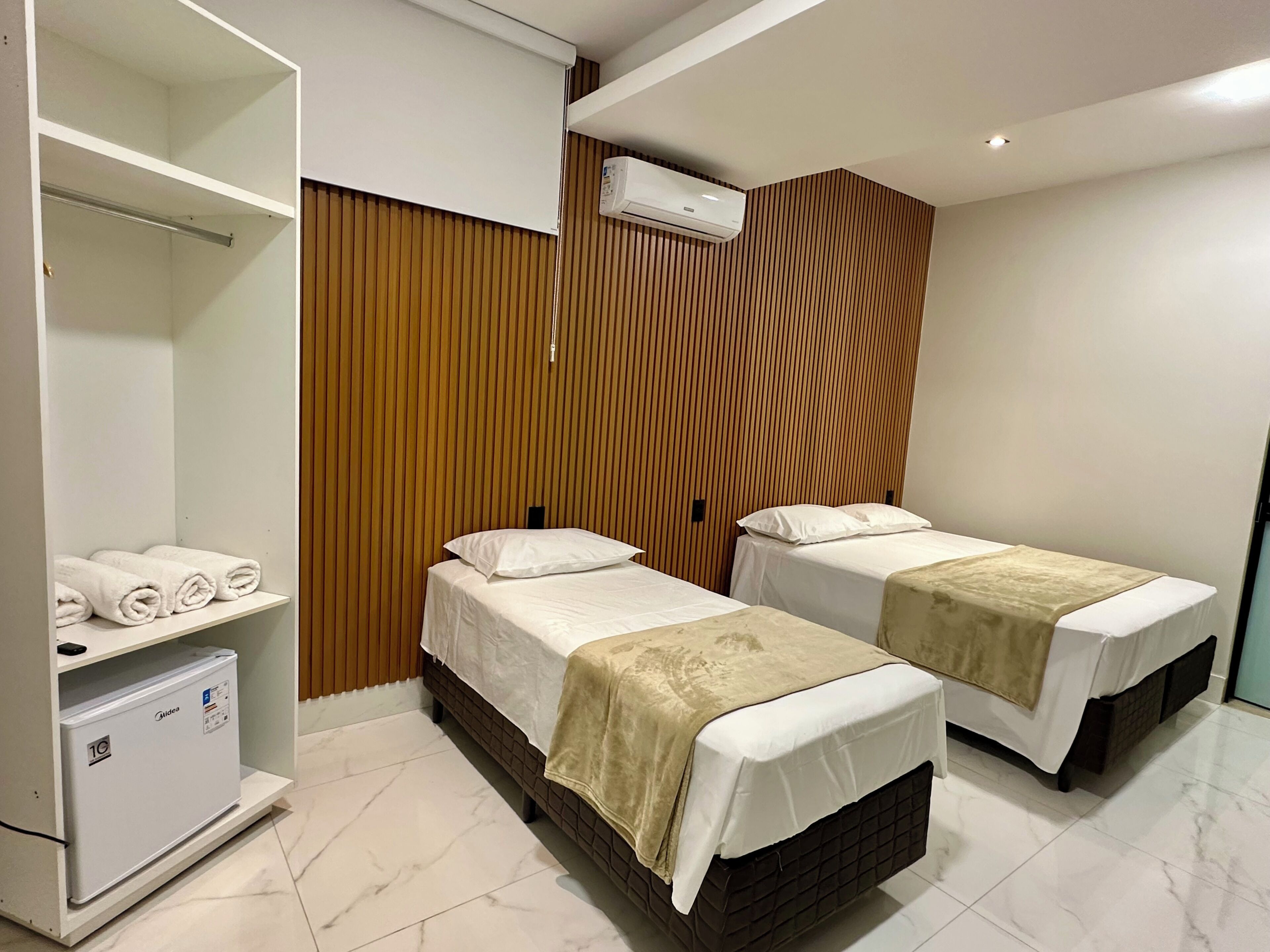 Une chambre d’hôtel avec deux lits, un minibar et une armoire.