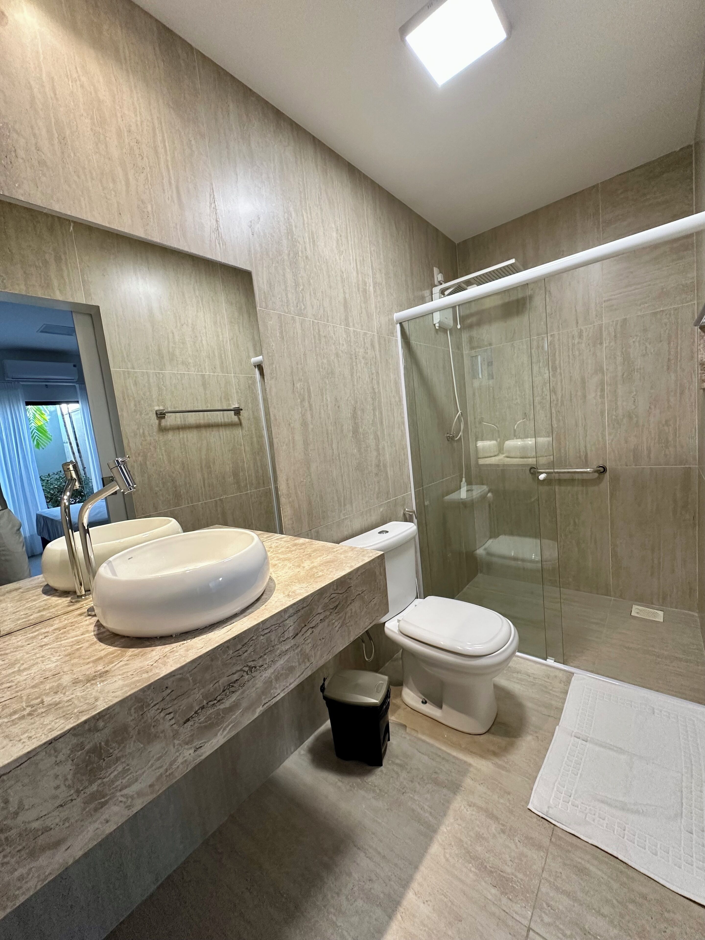 A modern bathroom with a large sink, toilet, and glass-enclosed shower.