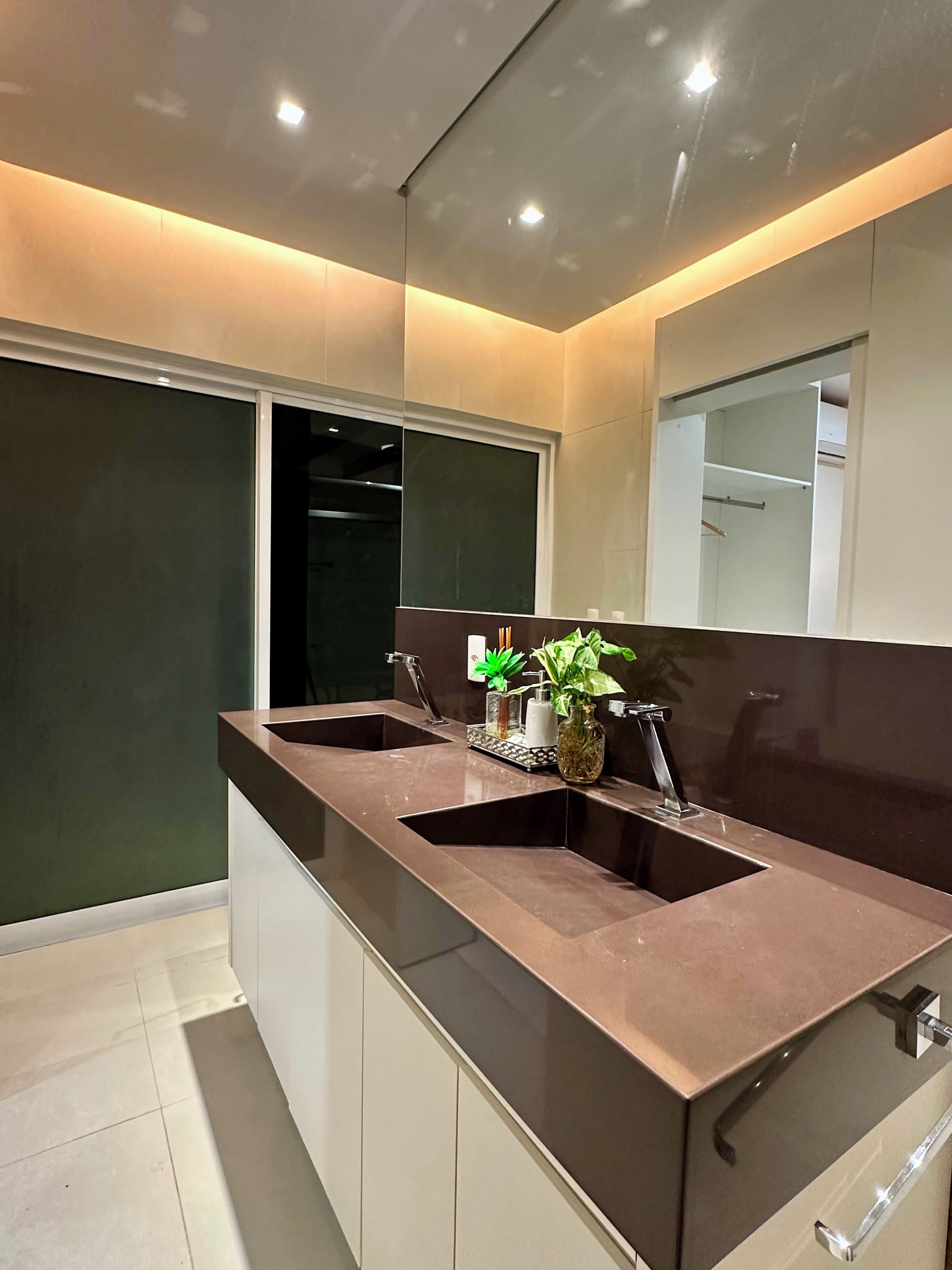 A modern bathroom with a dual sink vanity, a mirror, and a potted plant.