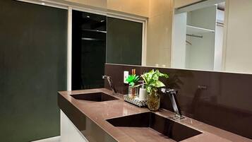 A modern bathroom with a dual sink vanity, a mirror, and a potted plant.