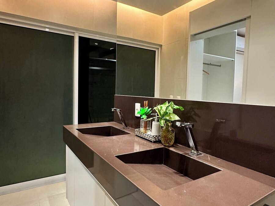 A modern bathroom with a dual sink vanity, a mirror, and a potted plant.