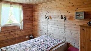 A wooden-paneled room with a bed, two wall-mounted lamps, and a window with curtains. - Beautiful home in Reksteren with WiFi (Reksteren)