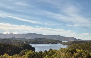 A panoramic view of a lake surrounded by hills with wind turbines in the distance.