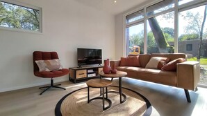 Una sala de estar moderna con un sofá, un sillón rojo, un televisor y una mesa de centro.