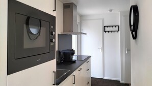 Una cocina compacta equipada con microondas, cafetera y cocina pequeña.