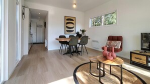 Una sala moderna con comedor, un ventanal grande y un televisor.