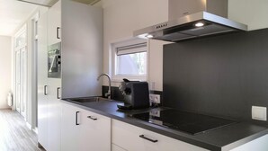 Una cocina moderna con encimera negra, electrodomésticos de acero inoxidable y un ventanal sobre el fregadero.