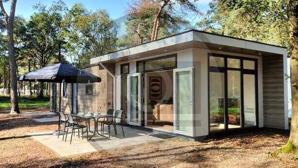 Un área de comedor exterior moderna con una mesa, sillas, un paraguas negro y una puerta de cristal que da a un edificio.