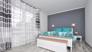 A bedroom with a bed, a bench, a nightstand, and a wall-mounted light fixture. - Awesome home in Villecroze (Villecroze)