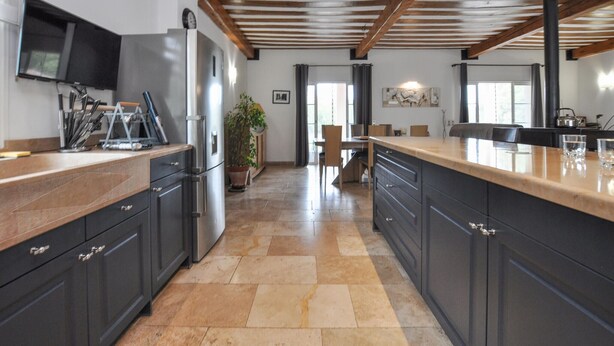 A modern kitchen with dark cabinetry, a large island, and a wooden ceiling. - Awesome home in Villecroze (Villecroze)
