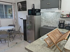 A compact kitchen with a refrigerator, microwave, coffee maker, and a small countertop.