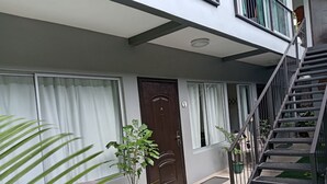 A modern building with a brown door, a staircase, and potted plants. - cr.arenalapartments #1 beautiful, comfortable with parking (La Fortuna)