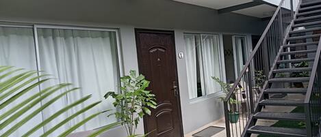 Un edificio moderno con una puerta marrón, una escalera y plantas en macetas.