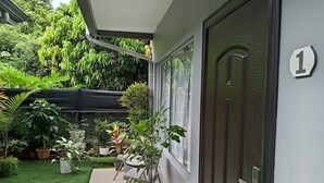 A covered outdoor area with a door marked '1', potted plants, and a small table with chairs. - cr.arenalapartments #1 beautiful, comfortable with parking (La Fortuna)
