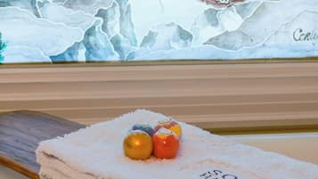 A towel with 'SOOK HOUSE' text, a painting of a bird on a tree, and two wrapped chocolates on the towel.