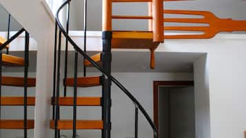 Una escalera en espiral con escalones de madera y barandillas negras, que conduce a un piso superior.