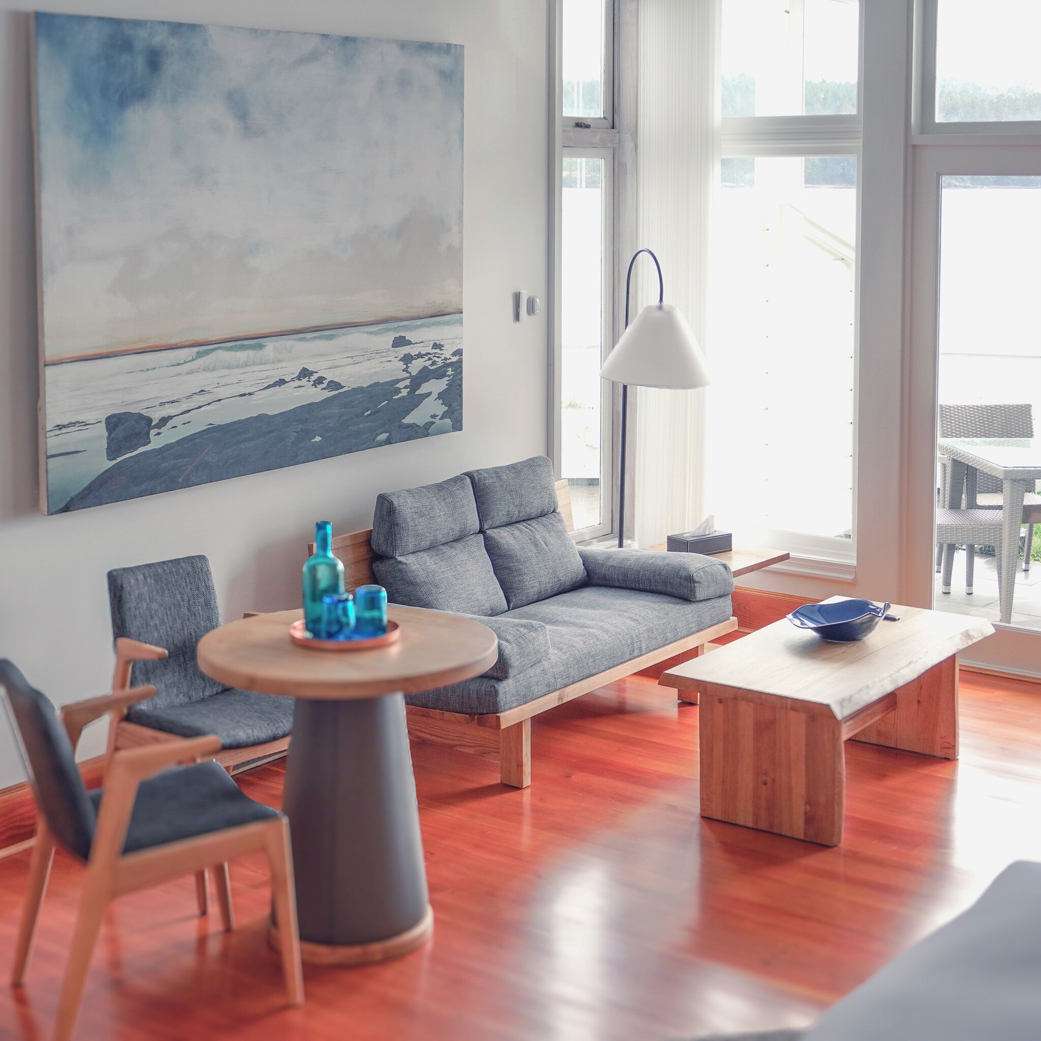 Ein modernes Wohnzimmer mit einem grauen Sofa, einem runden Holztisch und einer blauen Schüssel.
