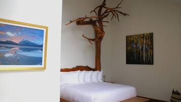 Een slaapkamer met een bed, een houten hoofdeinde en twee schilderijen aan de muur.