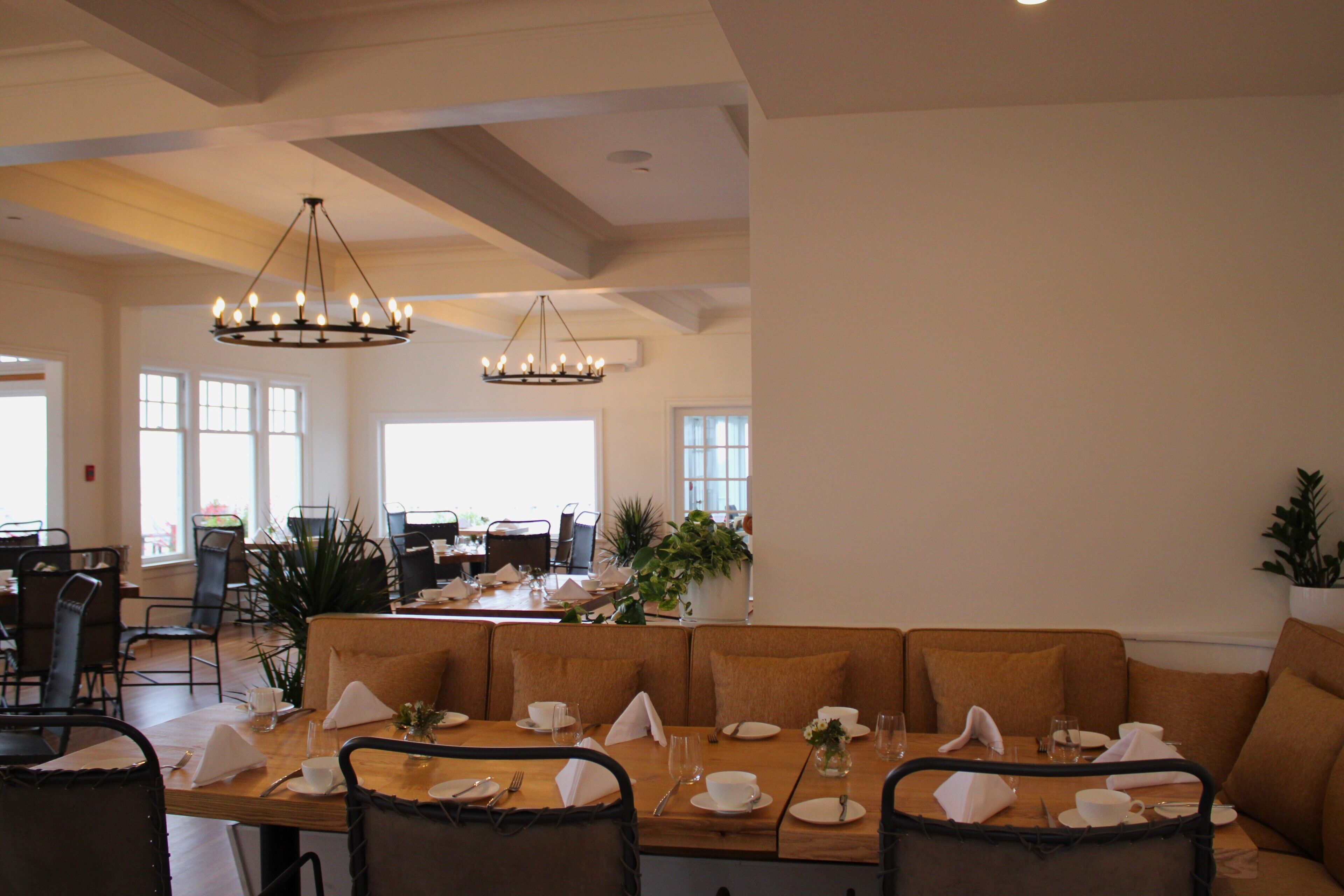 A spacious dining area with a long wooden table set for a meal, surrounded by cushioned seating.