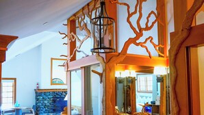 A room with a stone fireplace, wooden furniture, and a large mirror. - Sooke Harbour House (Sooke)