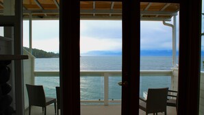 A balcony with two chairs facing a body of water and distant land. - Sooke Harbour House (Sooke)